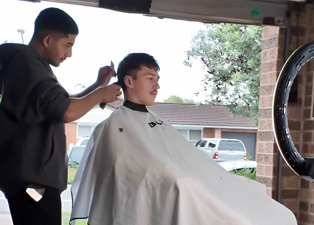 Stylist at Kavi's Kutz in Kariong, New South Wales, AU giving a fresh haircut to a customer in a vibrant setting.