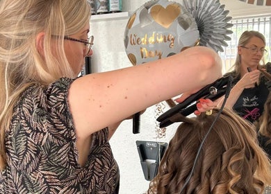 Stylist curling hair at D2 Hair Skin and Beauty in Worlingham, England, GB. Wedding decor in the background.
