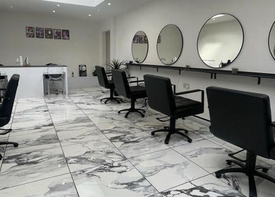 Elegant interior of Lauren Pomphrey Hairdressing in Andover, England showcasing sleek styling chairs and mirrors.