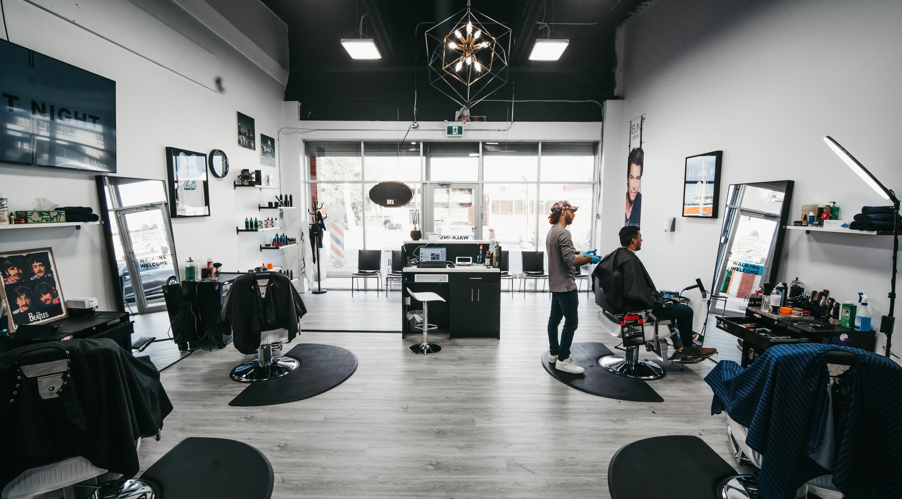 Interior of Macleod Trail Barbers in Calgary, Alberta, CA, featuring modern decor and barbers attending clients.