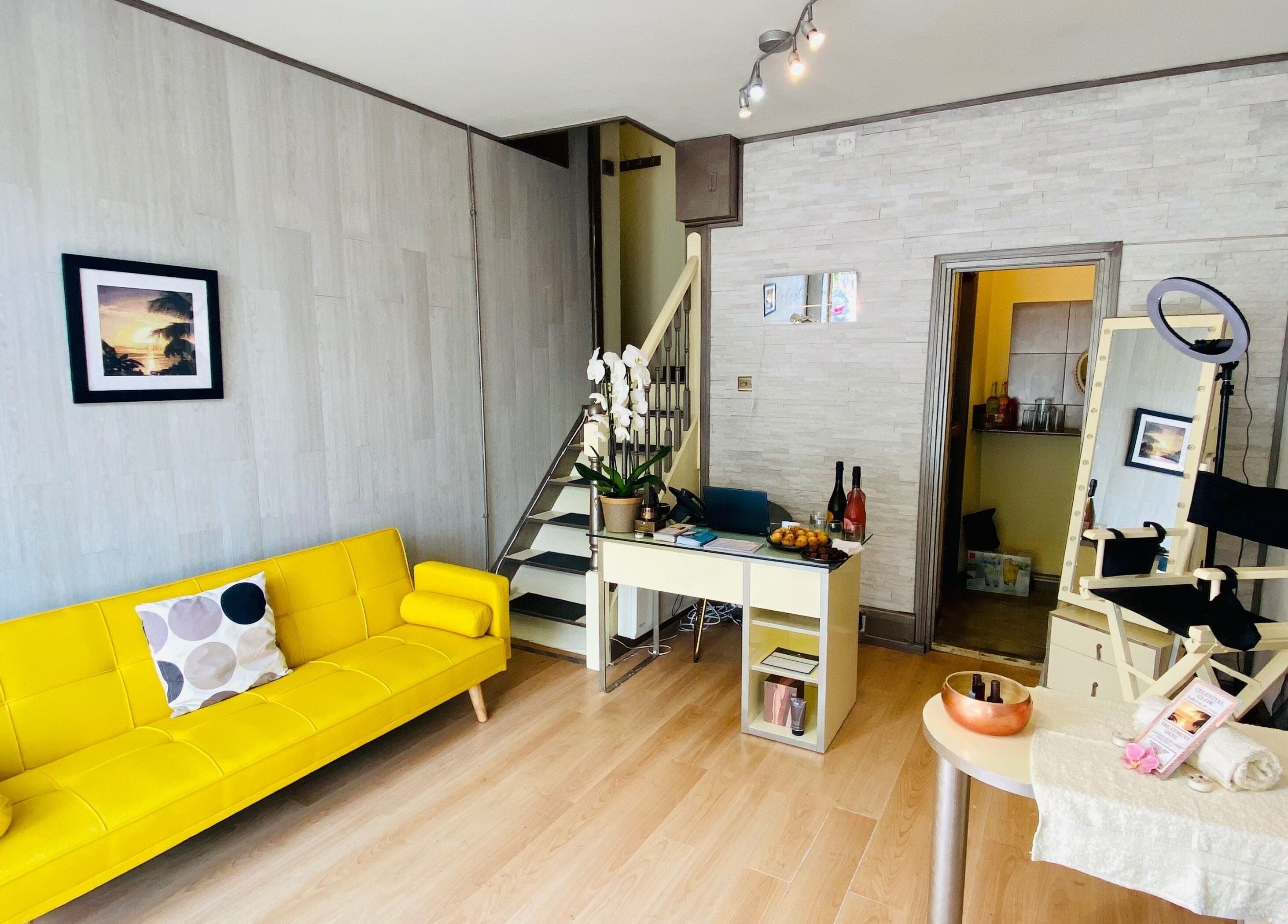 Bright, modern lounge at Celestial Glow, Brockenhurst, England, GB with yellow sofa and makeup station.