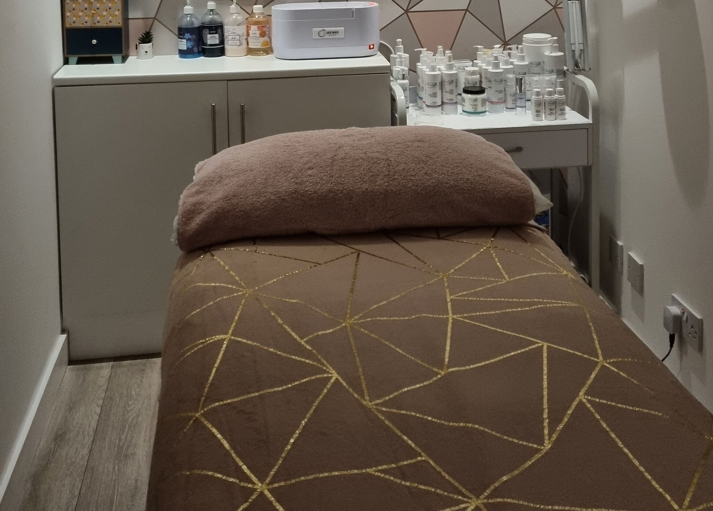 Relaxing treatment room at Loubelle Beauty, Aberdeen, Scotland, GB with a plush bed and skincare products.