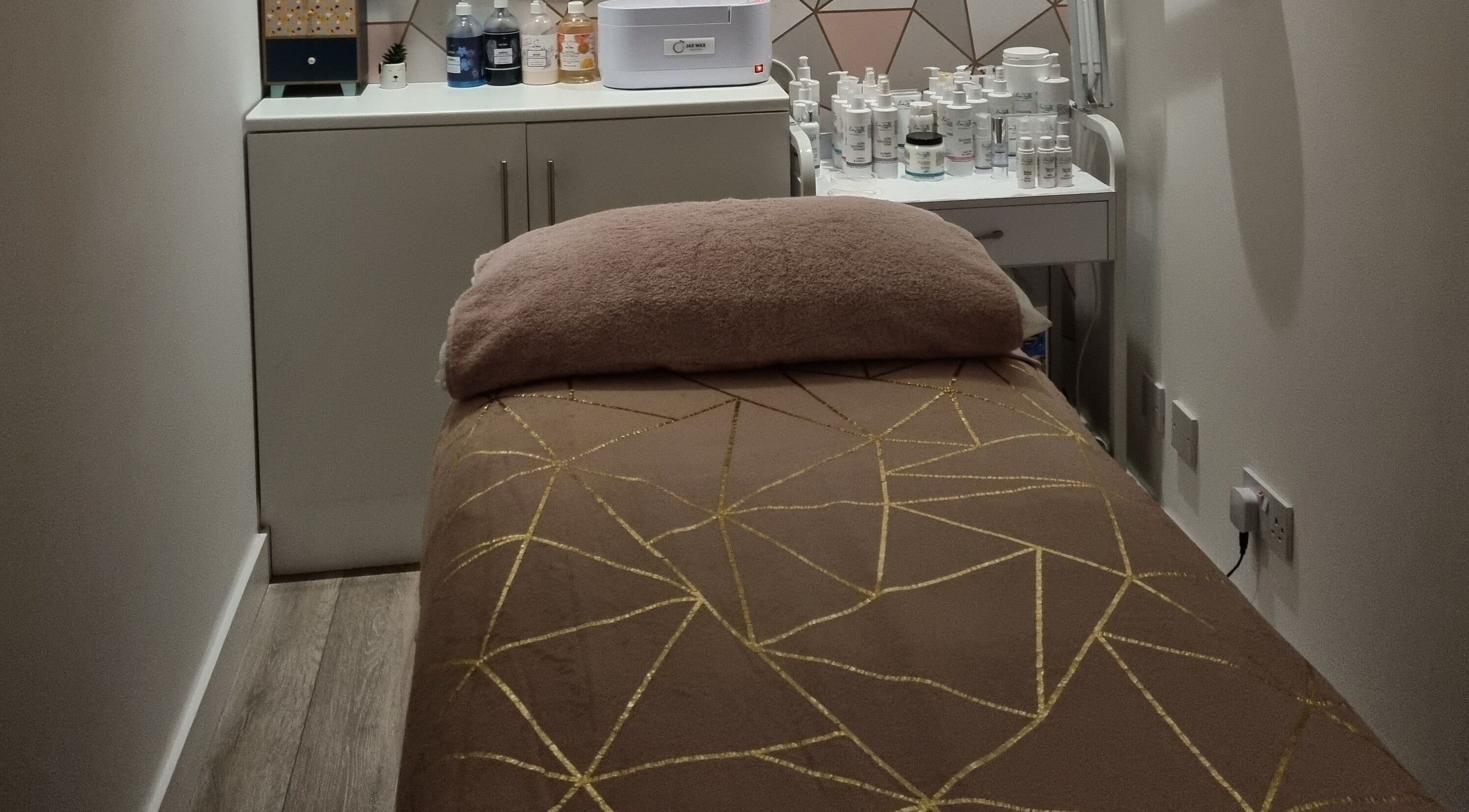 Relaxing treatment room at Loubelle Beauty, Aberdeen, Scotland, GB with a plush bed and skincare products.