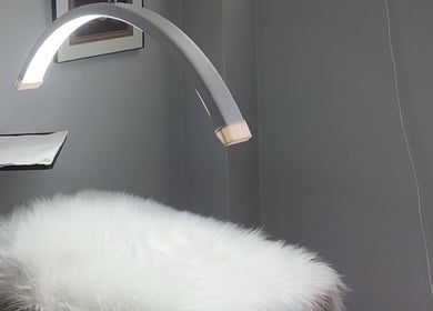 Serene treatment room at Femme Theory, London, Ontario, CA, featuring a plush white bed and sleek modern lamp.