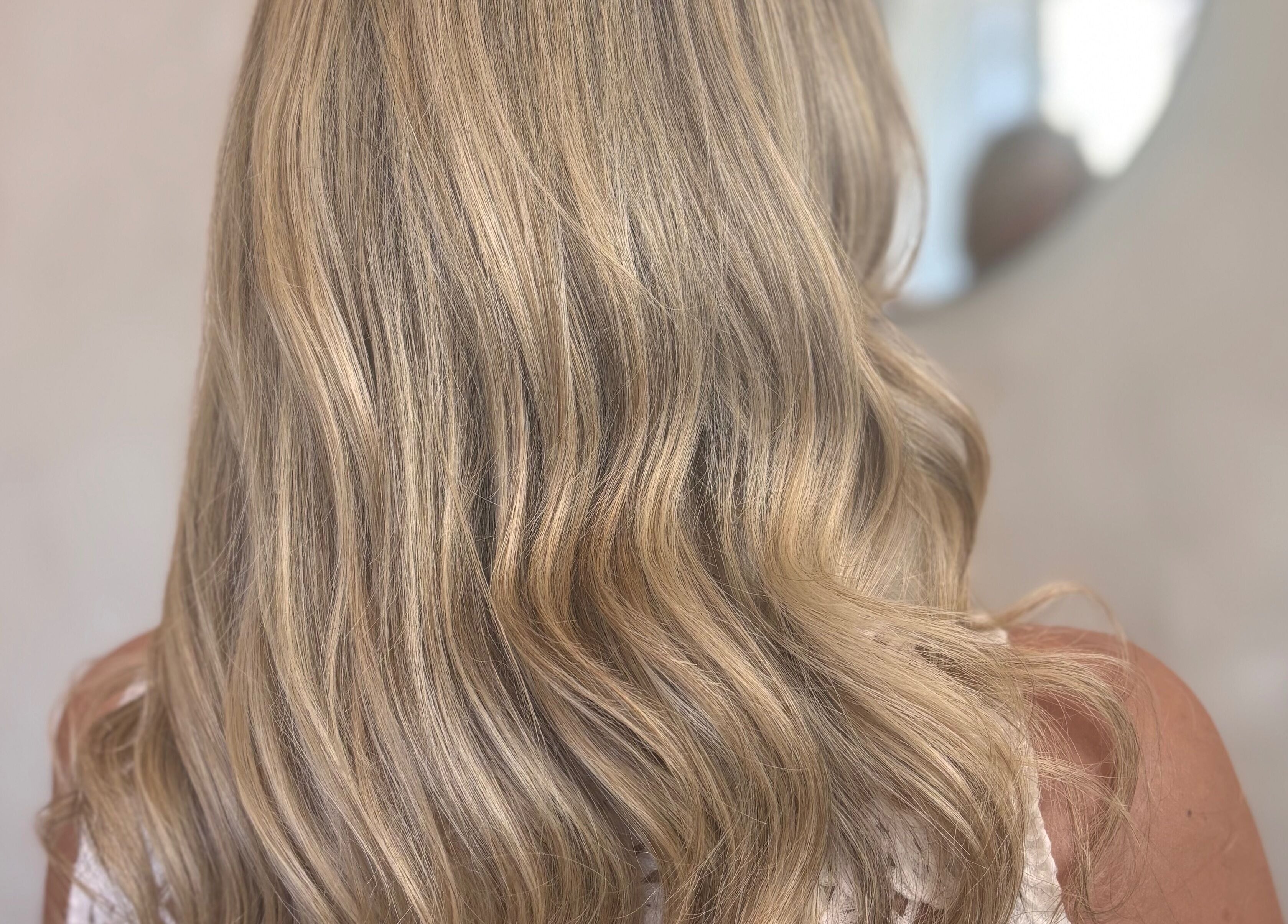 Golden blonde hair styled with soft waves at Signature Blonde in Leeds, England, GB.