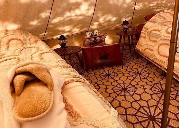 Inviting glamping setup at Be Well with Brooke, Oura, New South Wales, AU, featuring plush beds and lanterns.