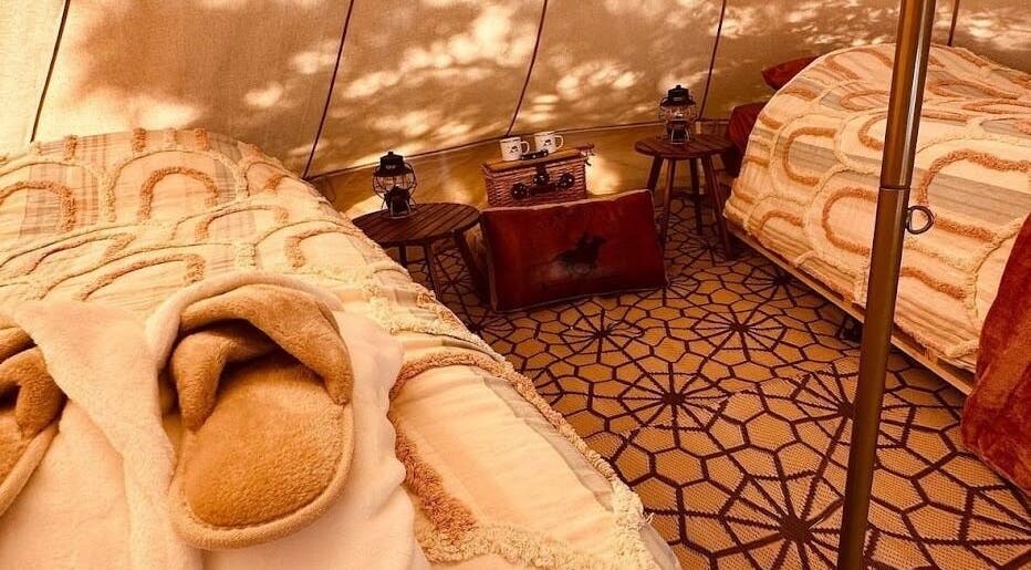 Inviting glamping setup at Be Well with Brooke, Oura, New South Wales, AU, featuring plush beds and lanterns.
