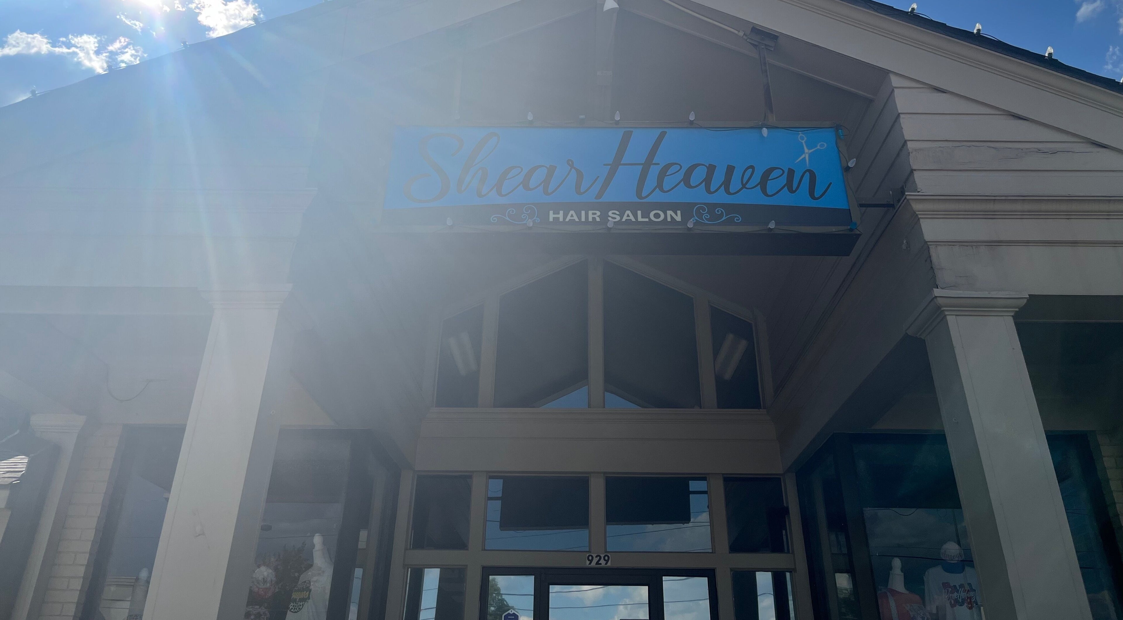 Entrance of Shear Heaven Salon in Ruston, Louisiana, with blue sky and sun rays highlighting the salon sign.