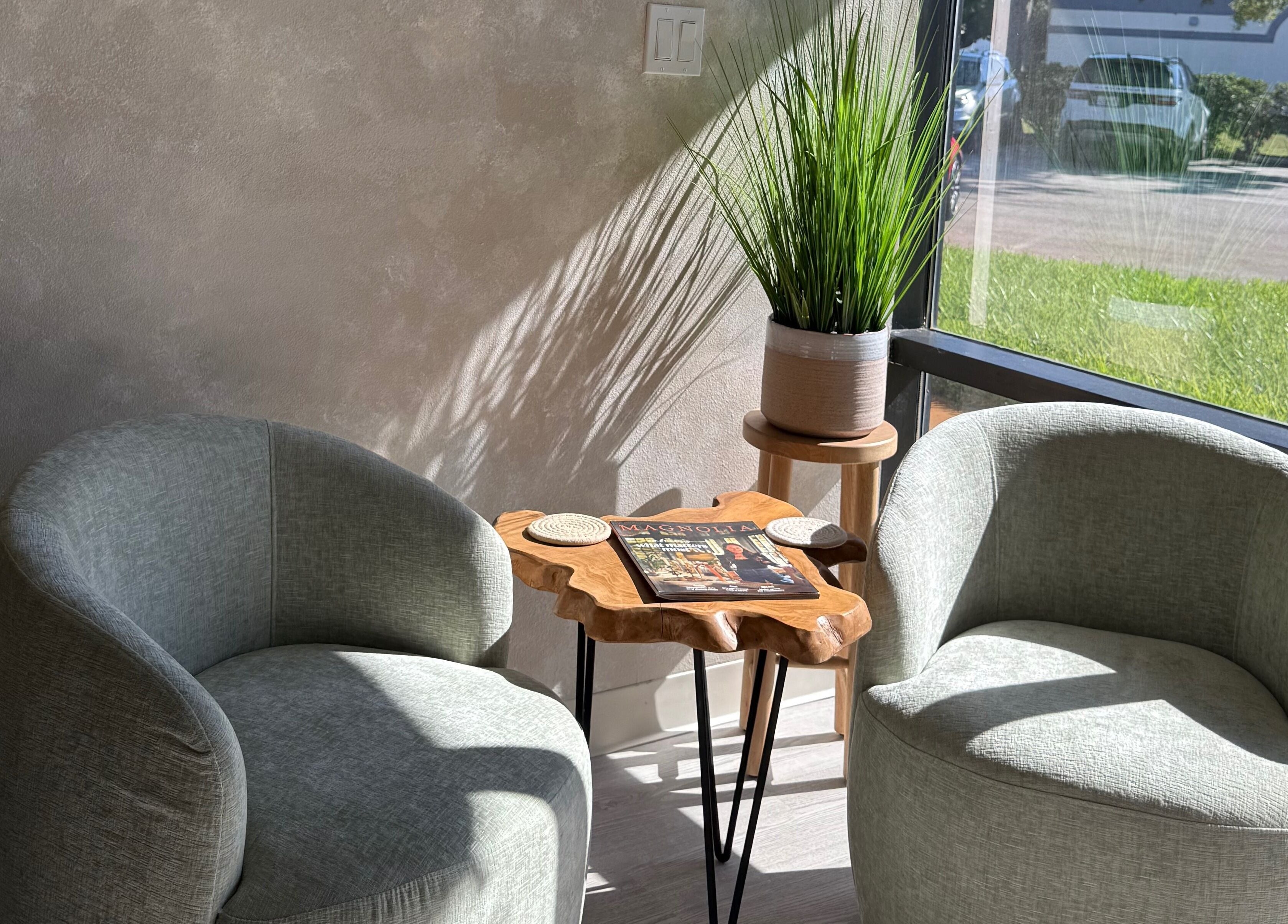 Two green chairs with a wooden table at Curated Color & Extensions, Tampa, Florida, US.