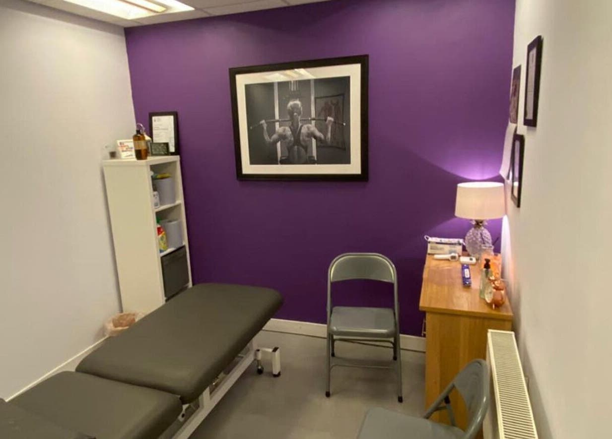 Cozy therapy room at Molly Sports Massage, Locker 27, Addlestone, England, with purple accent wall and massage table.