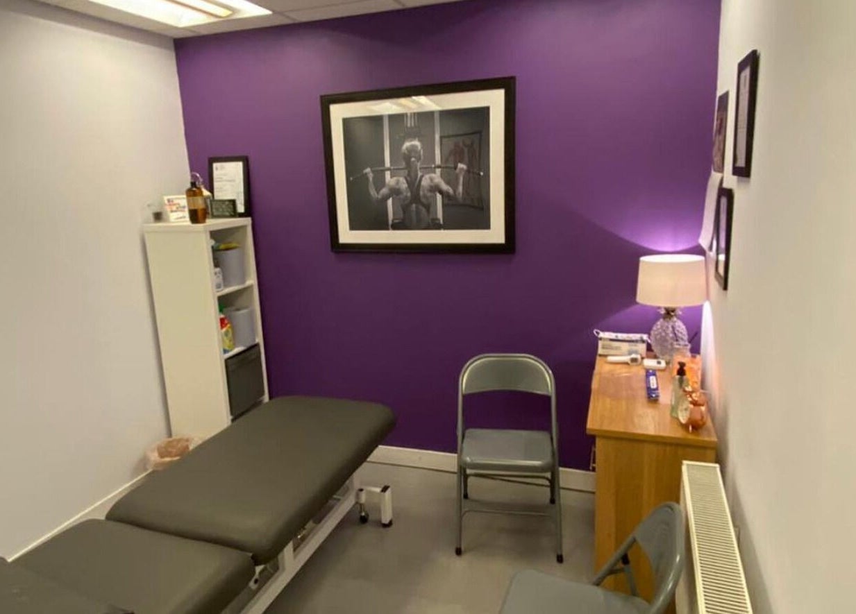 Cozy therapy room at Molly Sports Massage, Locker 27, Addlestone, England, with purple accent wall and massage table.
