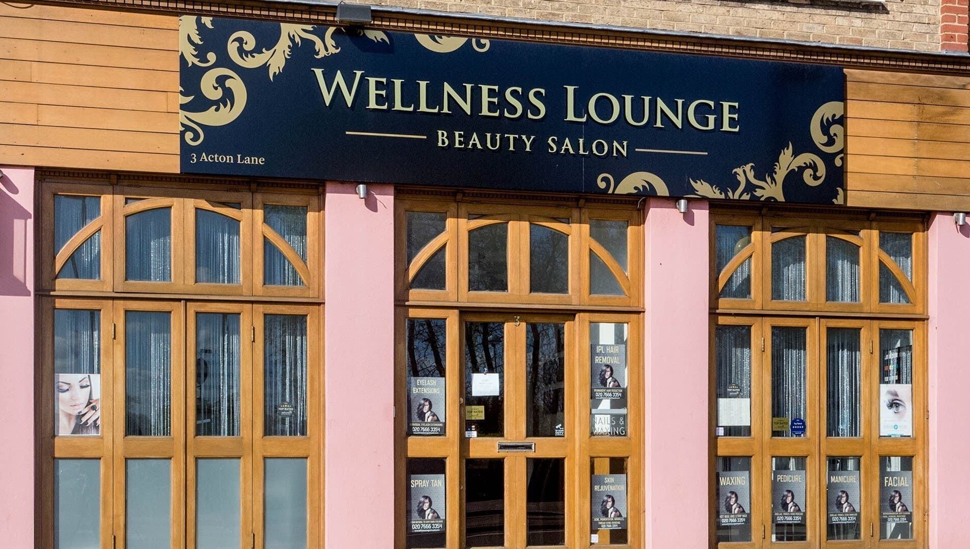 Front view of Wellness Lounge beauty salon, London, England, GB, with stylish wooden doors and signage.