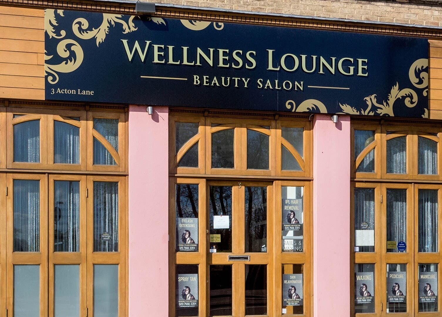 Front view of Wellness Lounge beauty salon, London, England, GB, with stylish wooden doors and signage.