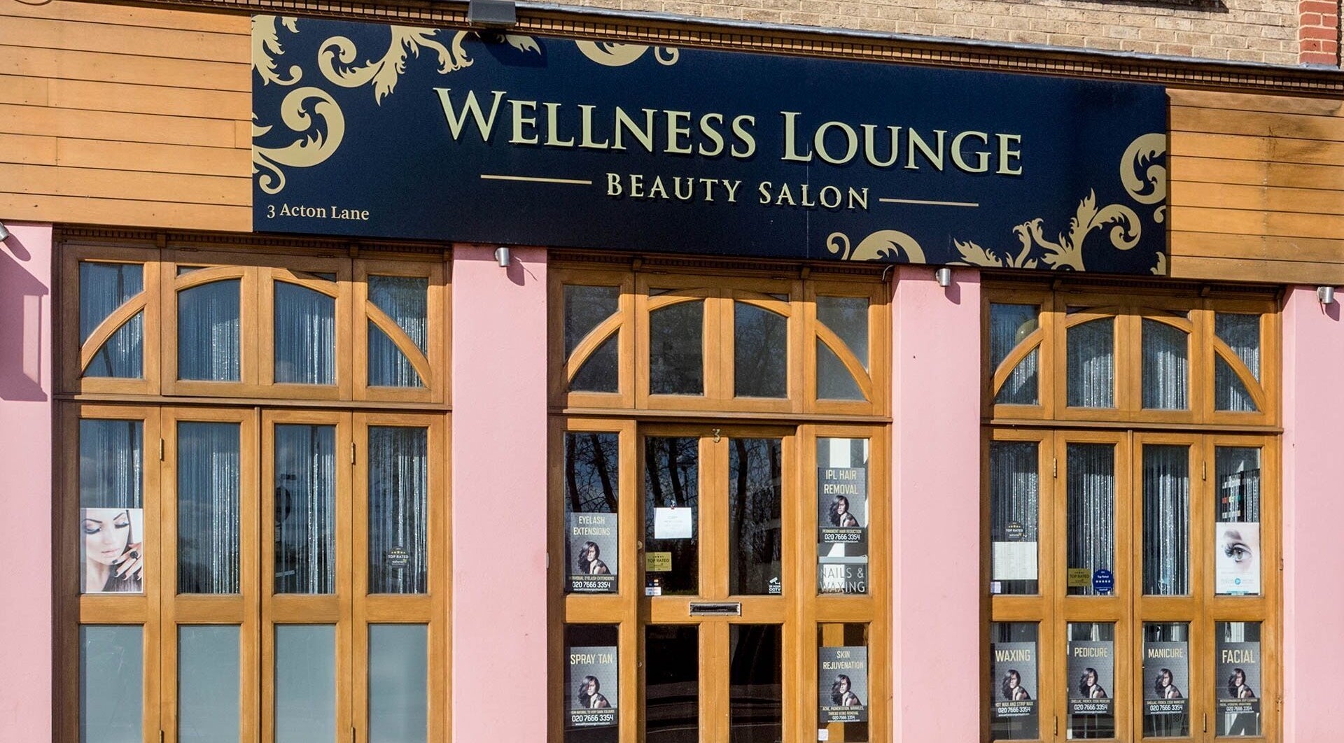 Front view of Wellness Lounge beauty salon, London, England, GB, with stylish wooden doors and signage.