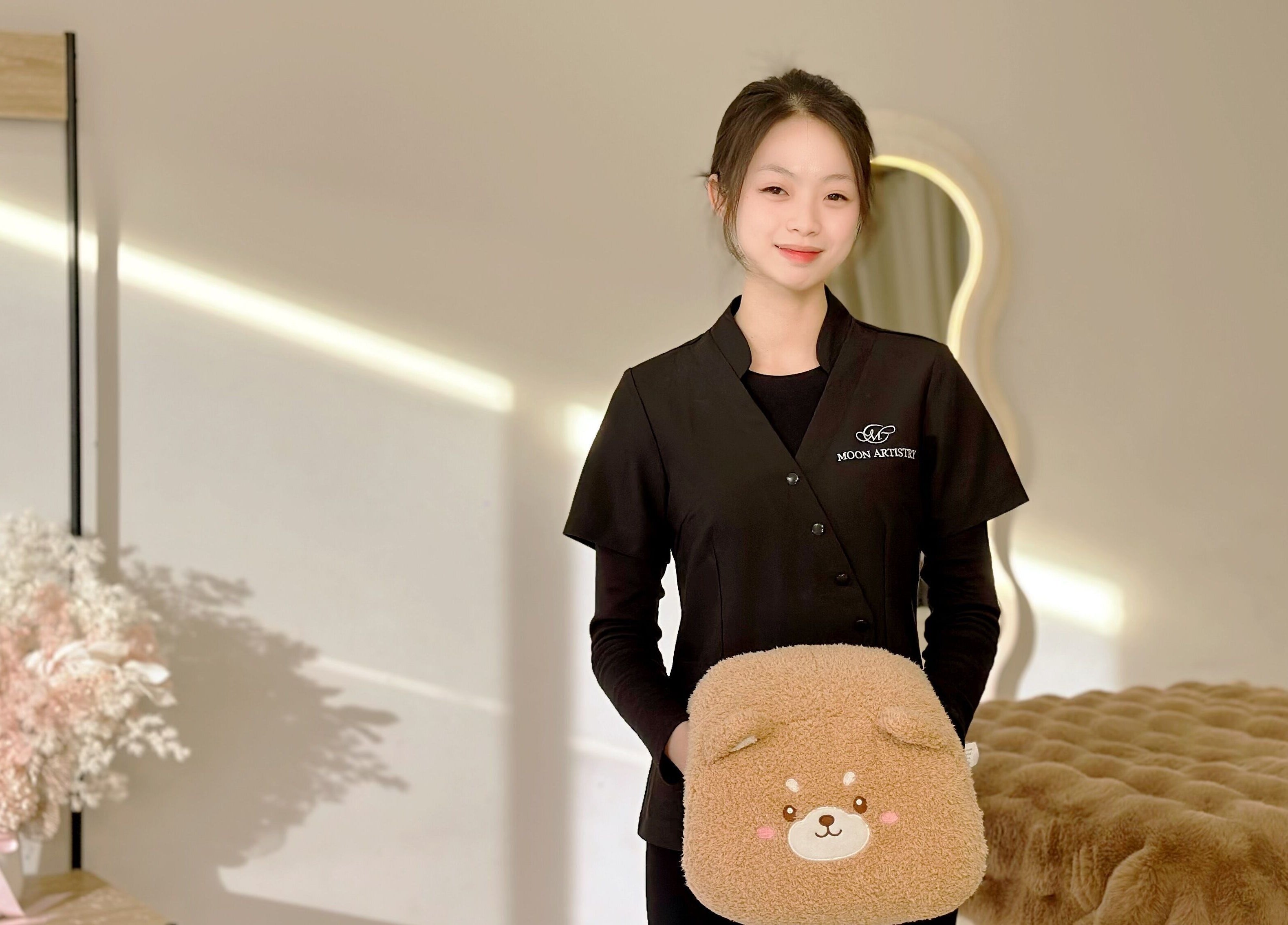 Expert at Moon Artistry Canley Vale holds a plush pillow in a serene treatment room, Canley Vale, New South Wales, AU.