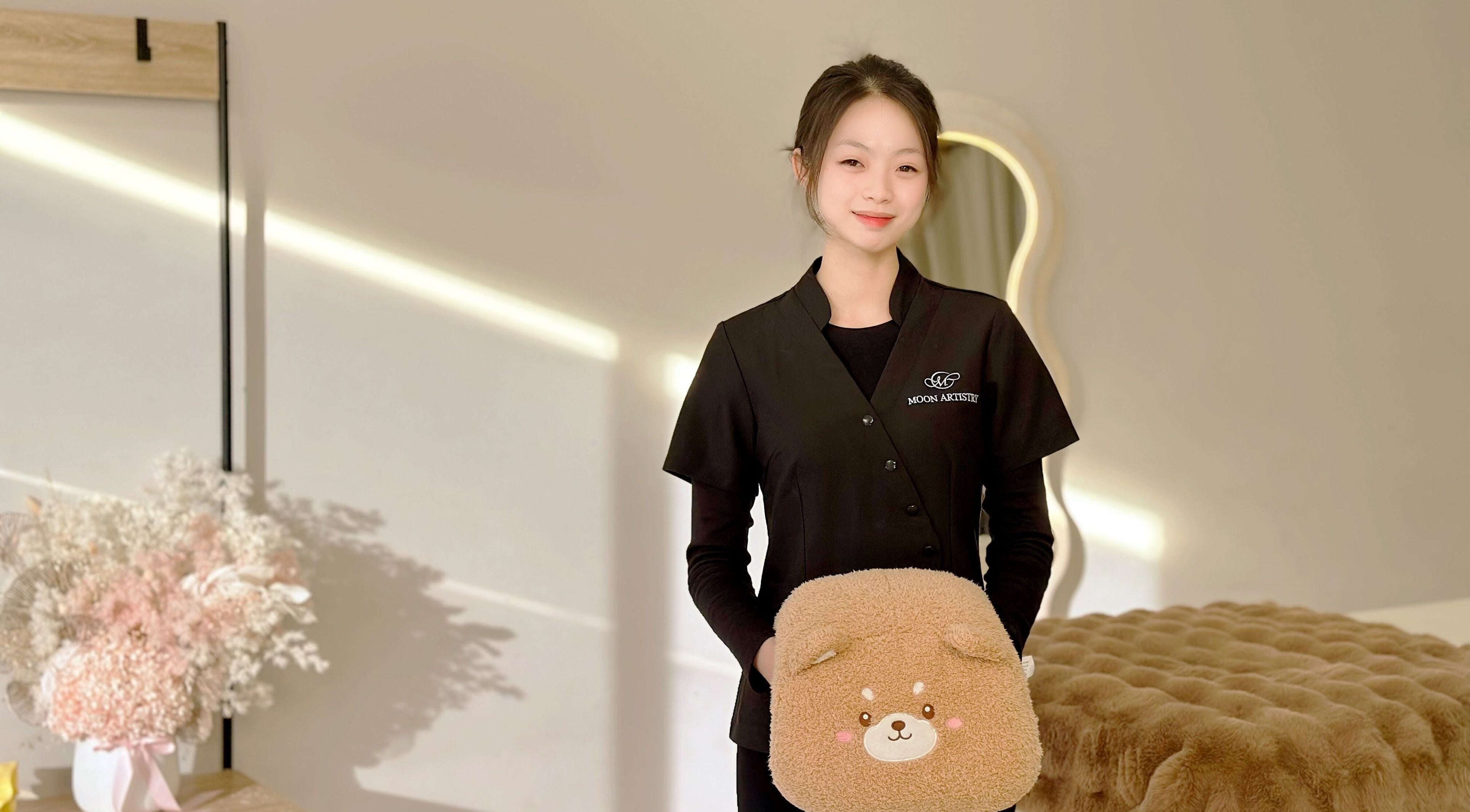 Expert at Moon Artistry Canley Vale holds a plush pillow in a serene treatment room, Canley Vale, New South Wales, AU.