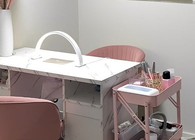 Elegant nail salon setup at Marble Beauty Bar in Glasgow, Scotland, GB with chic pink seating and marble table.
