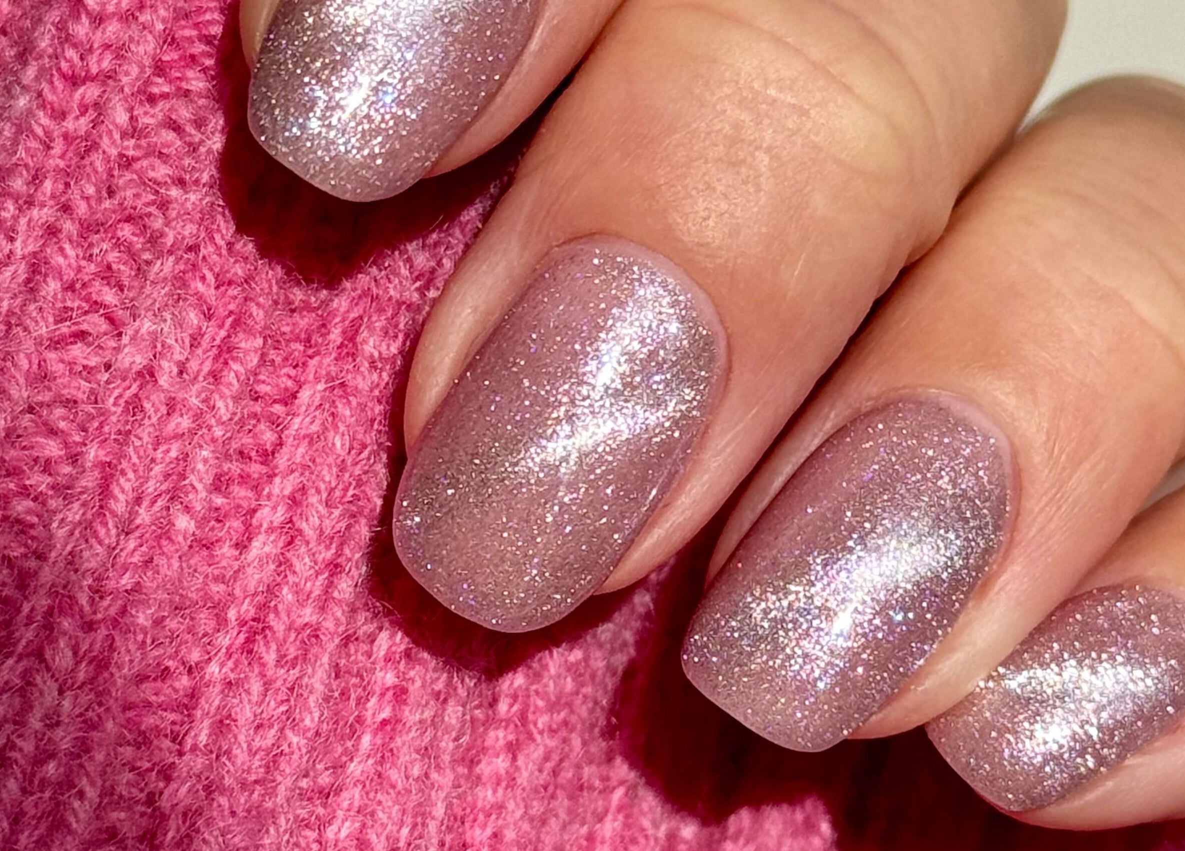 Glittery pink manicure at Painted Nails X Charlotte, Wokingham, England, GB on a cozy sweater.