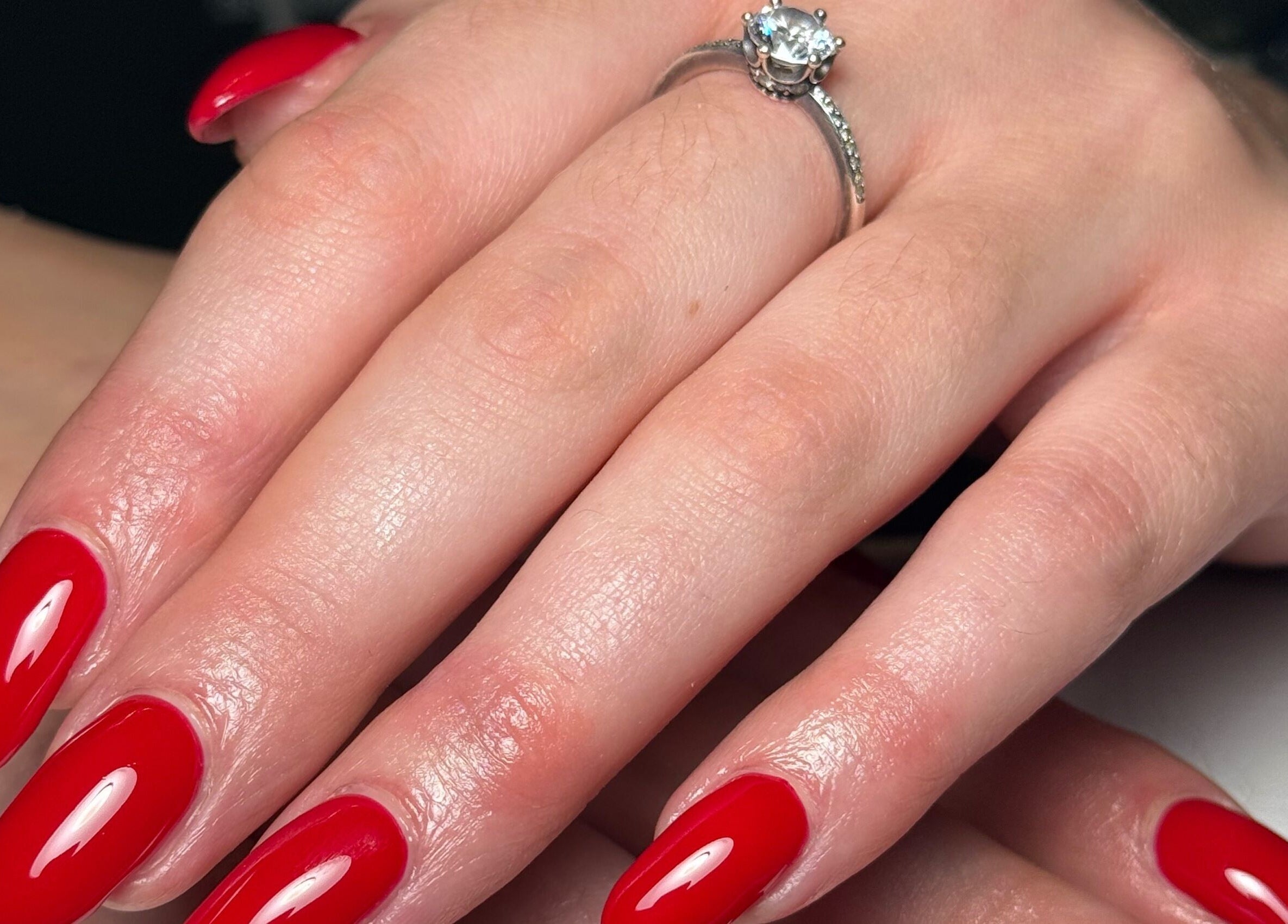 Bright red manicured nails from Painted Nails X Charlotte in Wokingham, England, GB with a diamond ring.