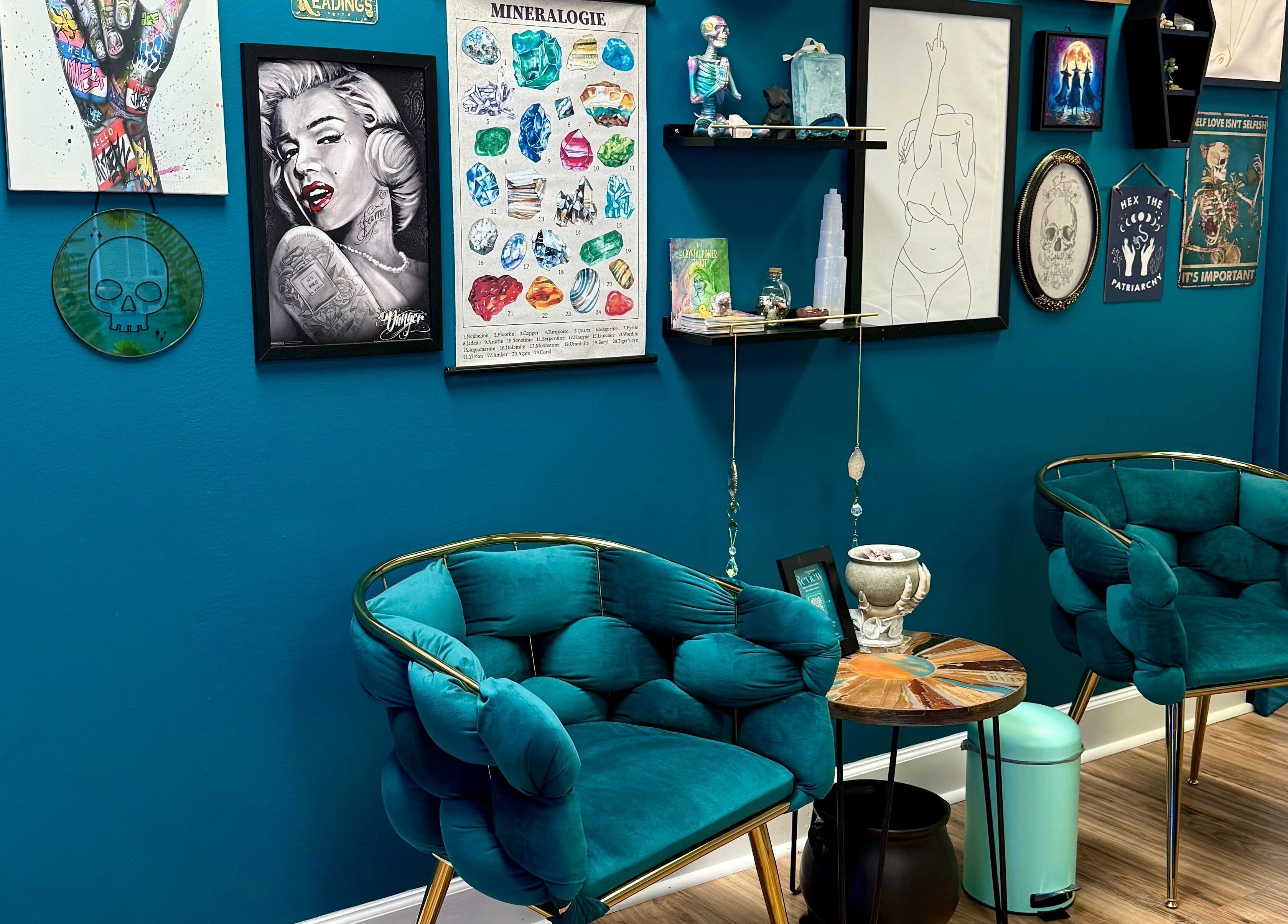 Art-filled lounge at Crystal Coven Waxing in Alexandria, Virginia, US, featuring teal chairs and eclectic wall decor.