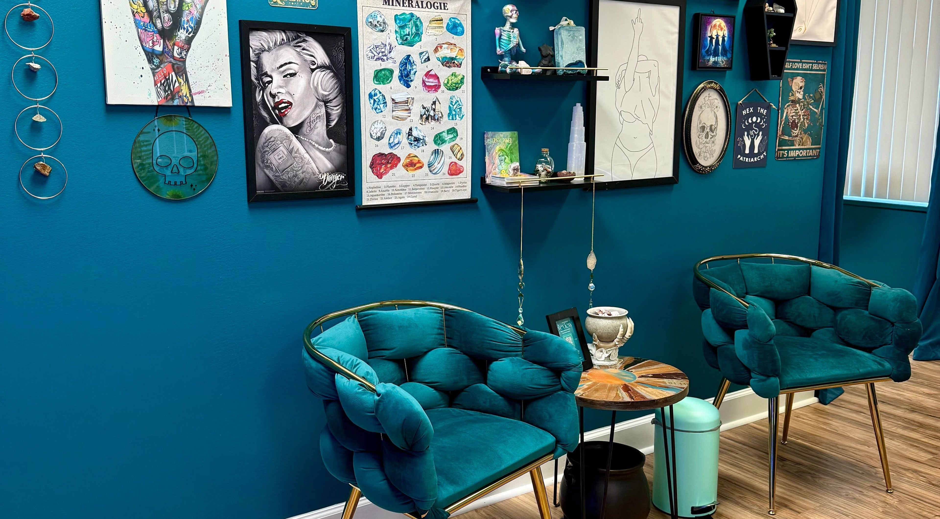 Art-filled lounge at Crystal Coven Waxing in Alexandria, Virginia, US, featuring teal chairs and eclectic wall decor.