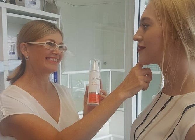 Smiling consultant at E-Sab Clinic, Benowa, Queensland, AU, applies skincare on a client.