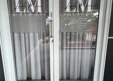 Glass door entrance of Hair by Laura Marie display business hours in Camden, New South Wales, AU.