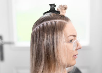 Hair extensions applied at Malibu Hair UK, Exeter, England, GB. Professional styling in progress.
