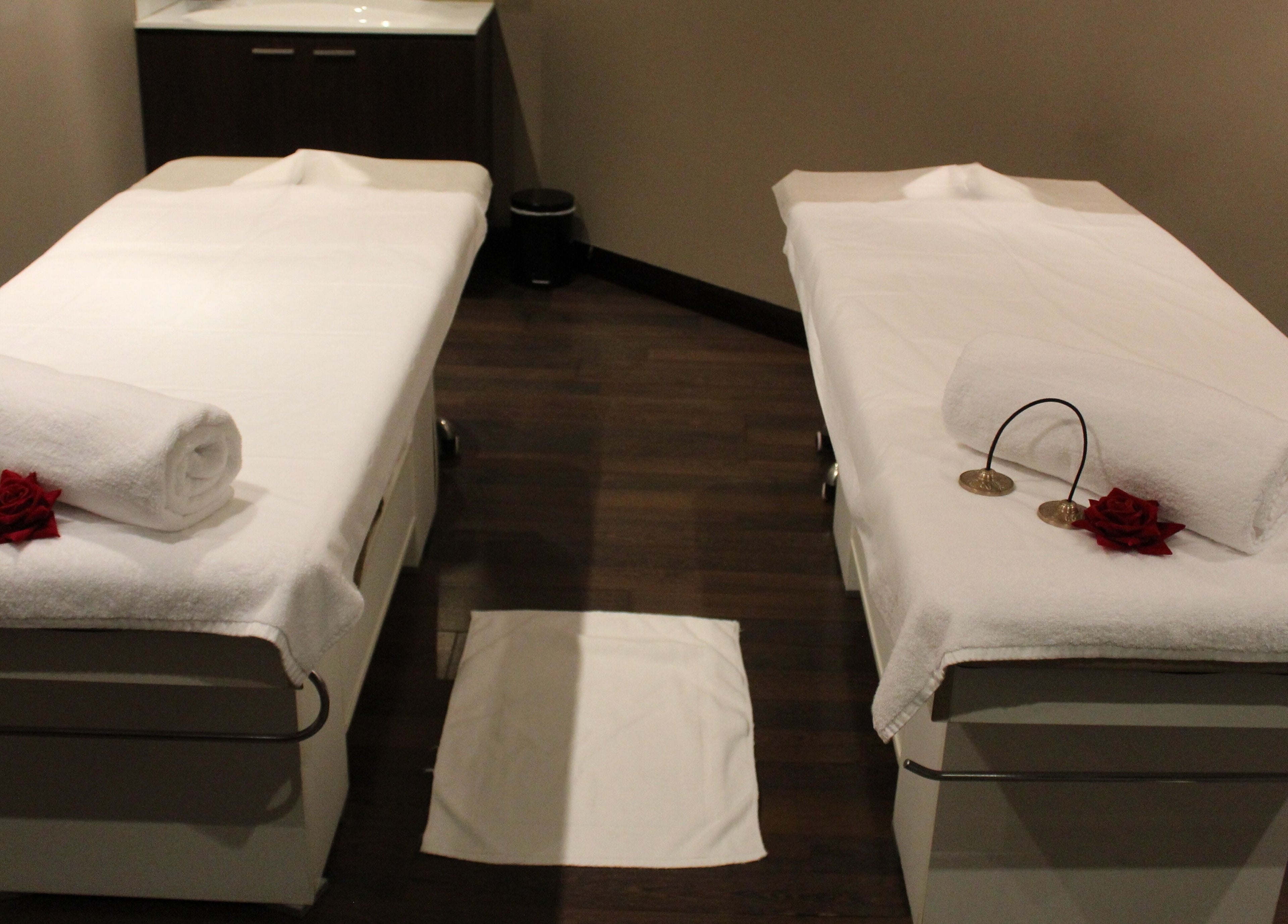 Twin massage beds at DWS-Palm Jumeirah in Dubai, AE, set up with towels and roses for relaxation.