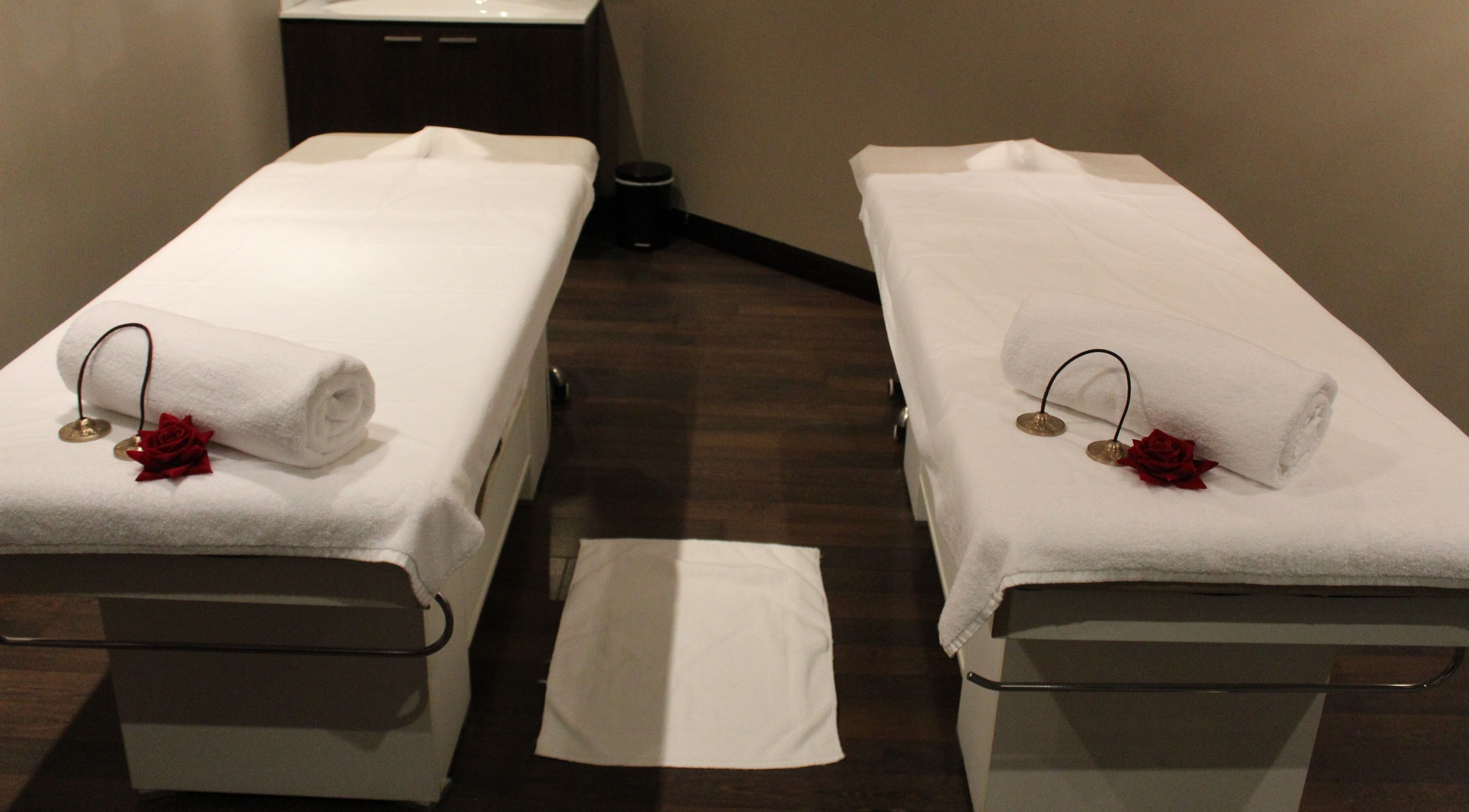 Twin massage beds at DWS-Palm Jumeirah in Dubai, AE, set up with towels and roses for relaxation.