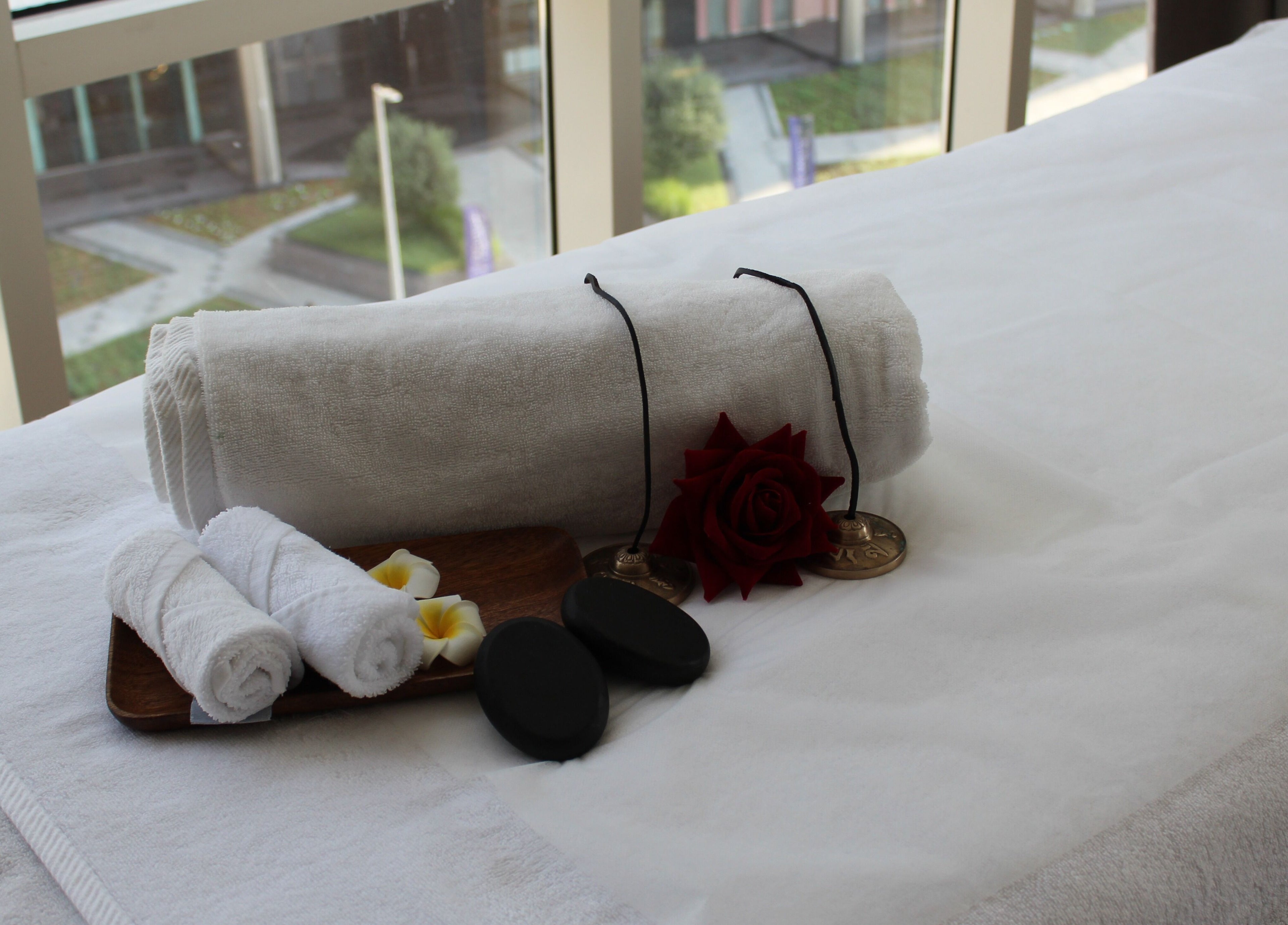 Relaxing spa setup at DWS-Radisson Canal View, Dubai. Elegant towels, flowers, and stones enhance tranquility.
