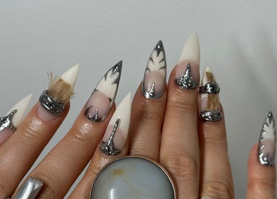 Intricate nail art with silver accents at Suki Nailz, London, England, GB. Unique designs on stiletto-shaped nails.