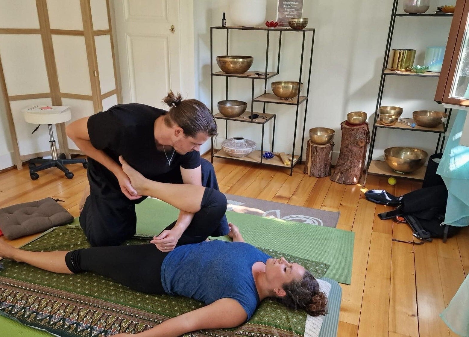 Therapist performs a leg stretch on a client at Izzy's Studio, Val De Bagnes, Valais, CH, enhancing relaxation.