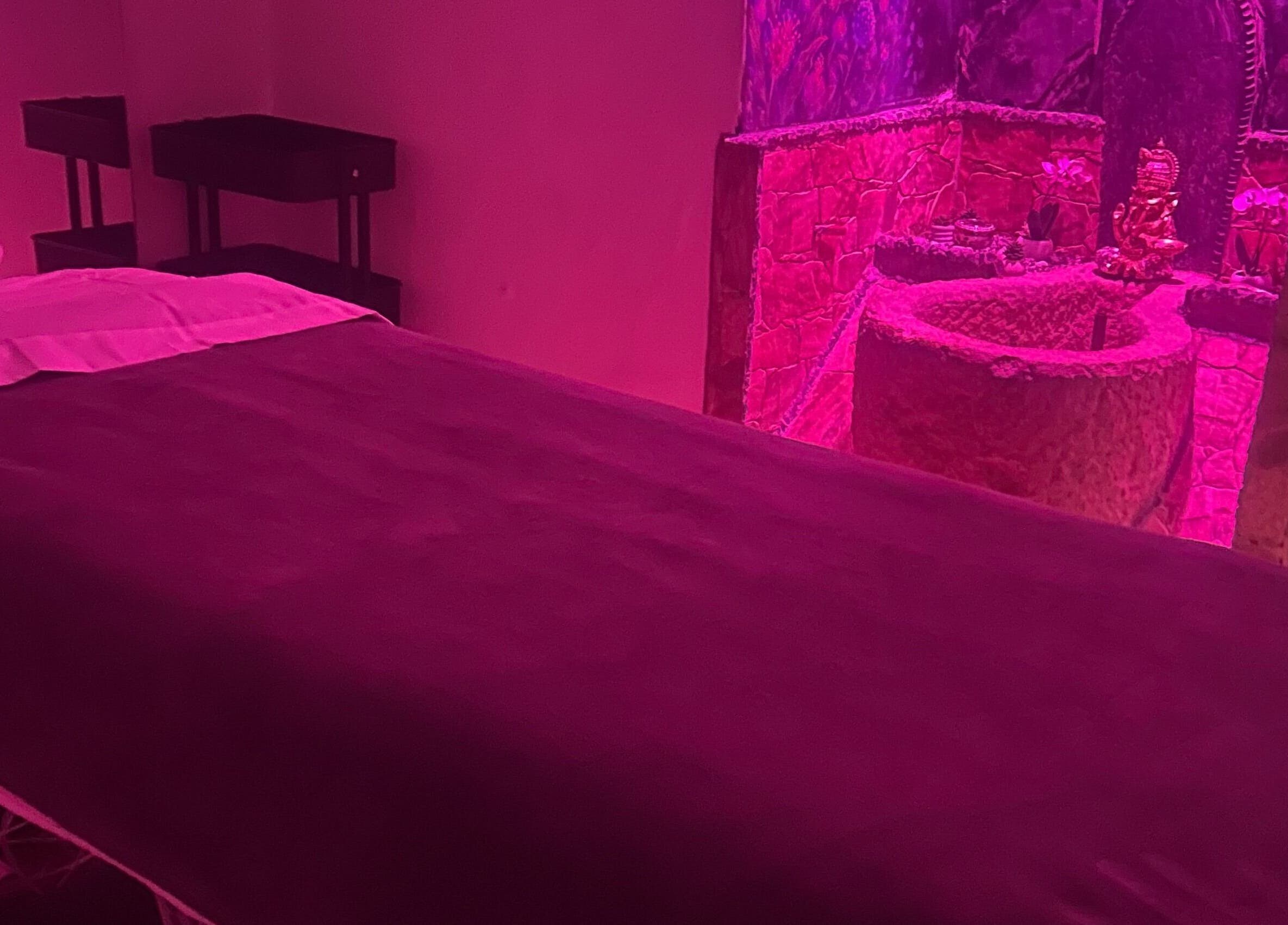 Dimly lit massage room at Izzy Spa in Val De Bagnes, Valais, CH with a serene, relaxing pink glow.