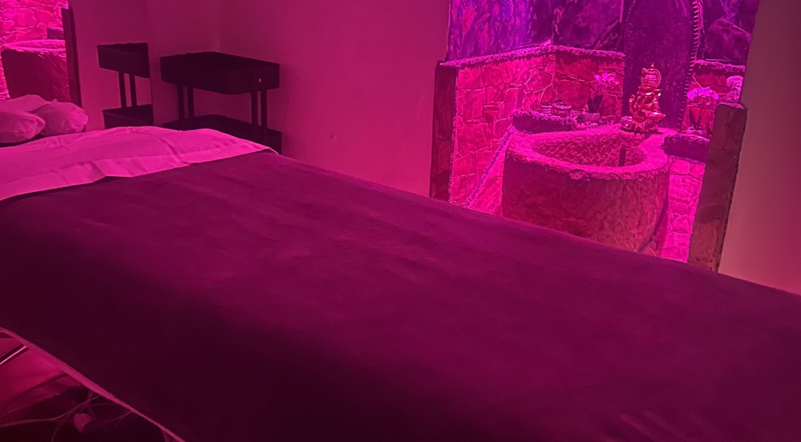 Dimly lit massage room at Izzy Spa in Val De Bagnes, Valais, CH with a serene, relaxing pink glow.