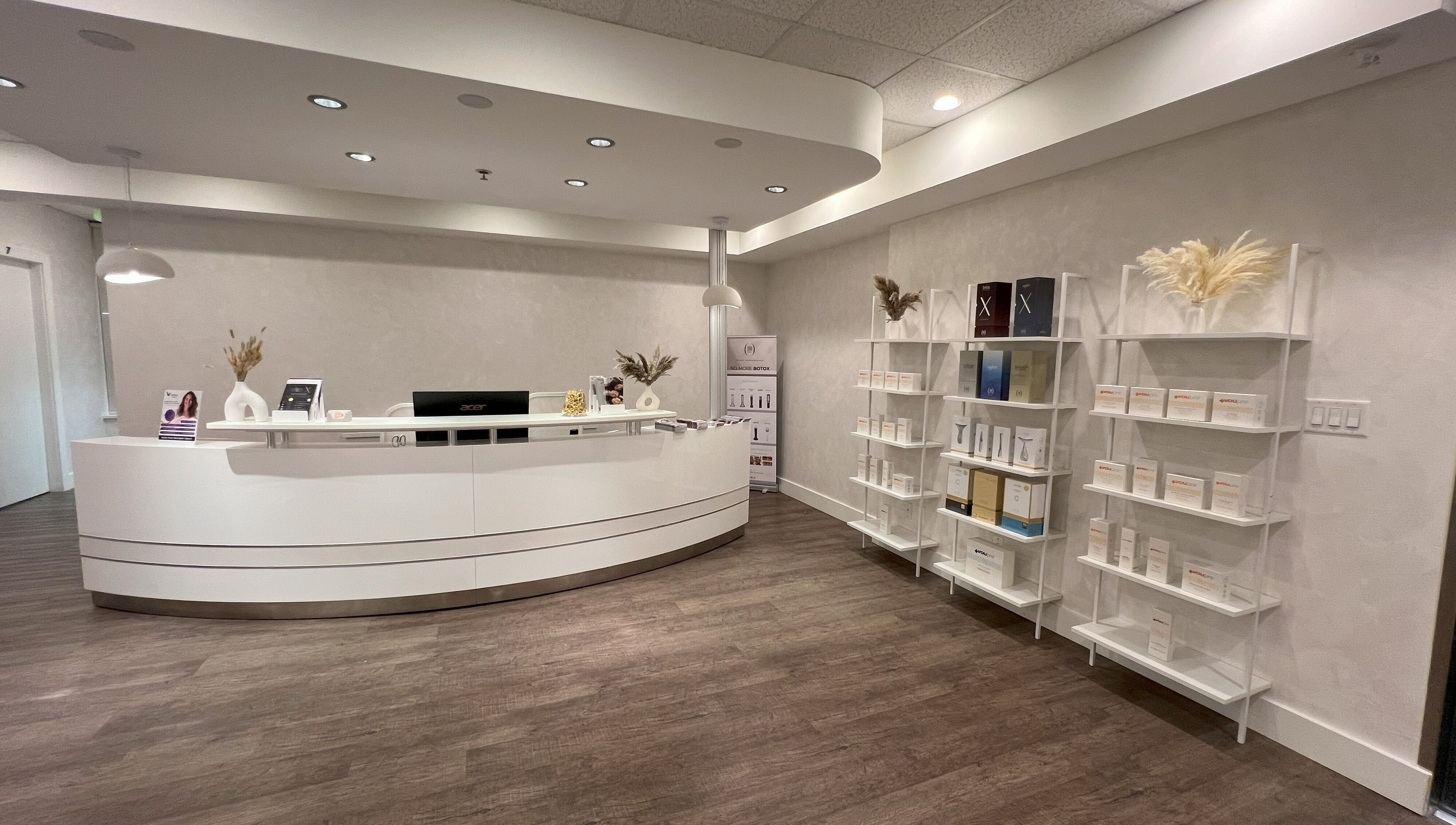 Oasis Aesthetics Spa - Marine's sleek reception in West Vancouver, British Columbia, CA with white desk and shelves.