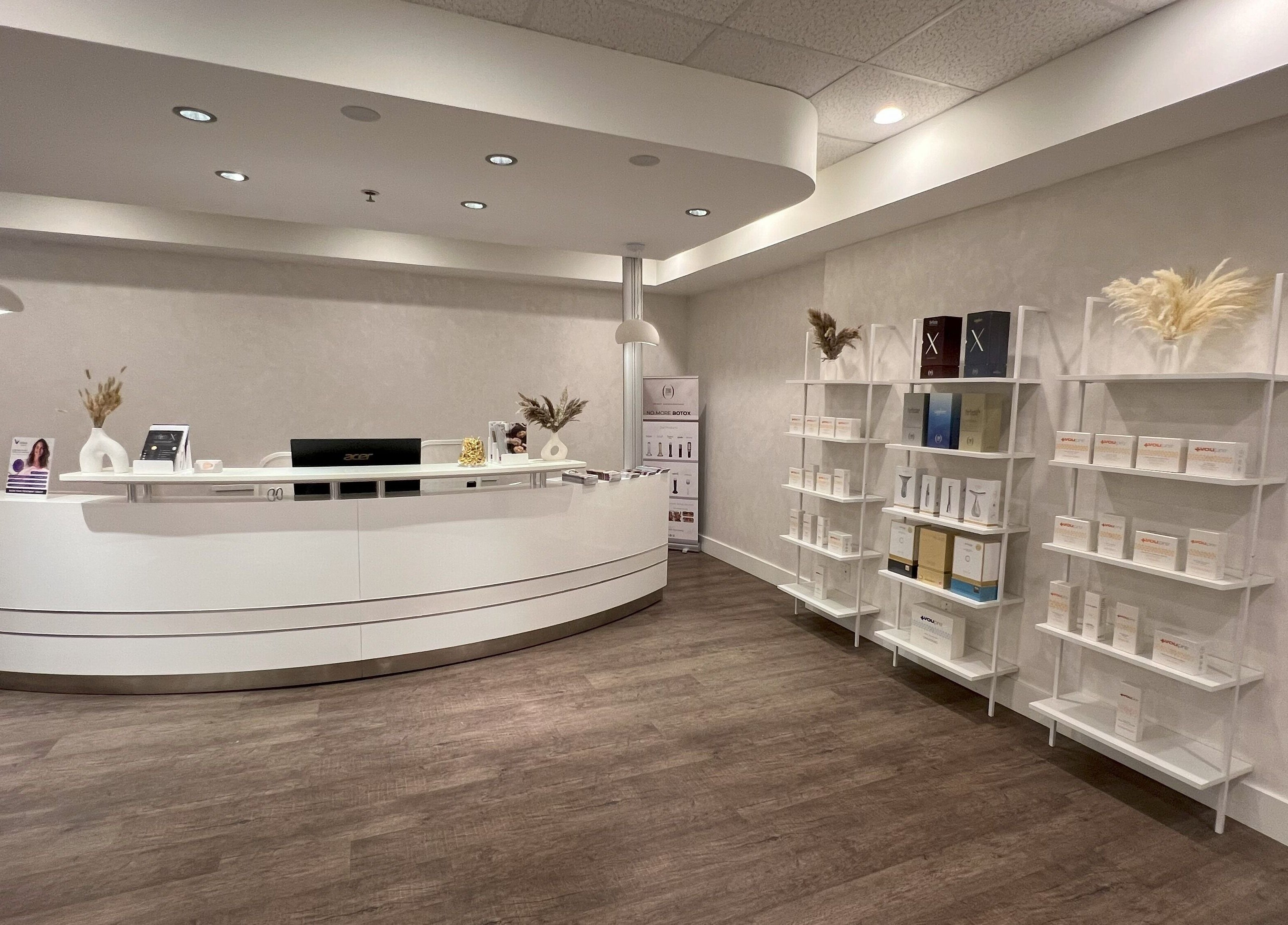 Oasis Aesthetics Spa - Marine's sleek reception in West Vancouver, British Columbia, CA with white desk and shelves.