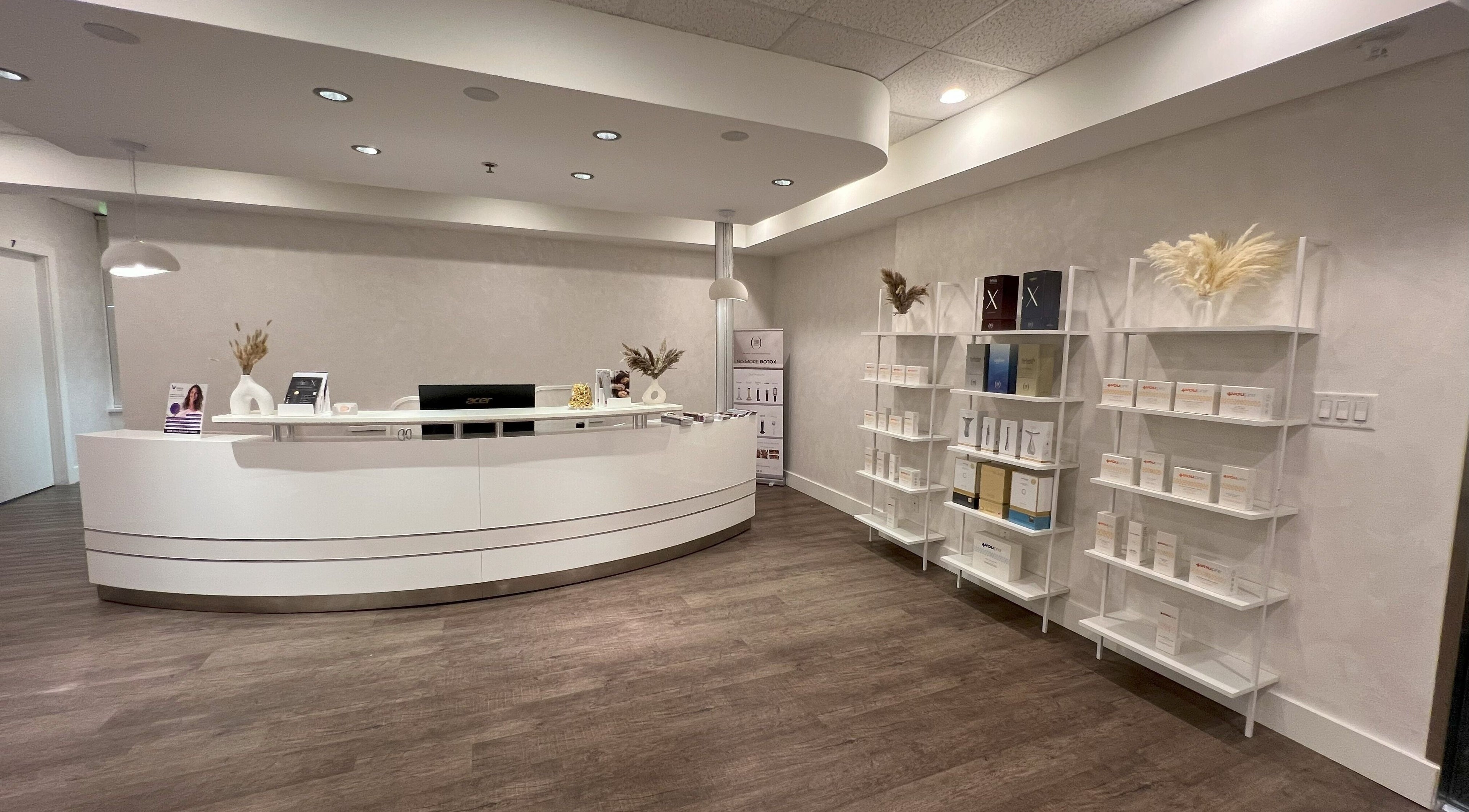 Oasis Aesthetics Spa - Marine's sleek reception in West Vancouver, British Columbia, CA with white desk and shelves.
