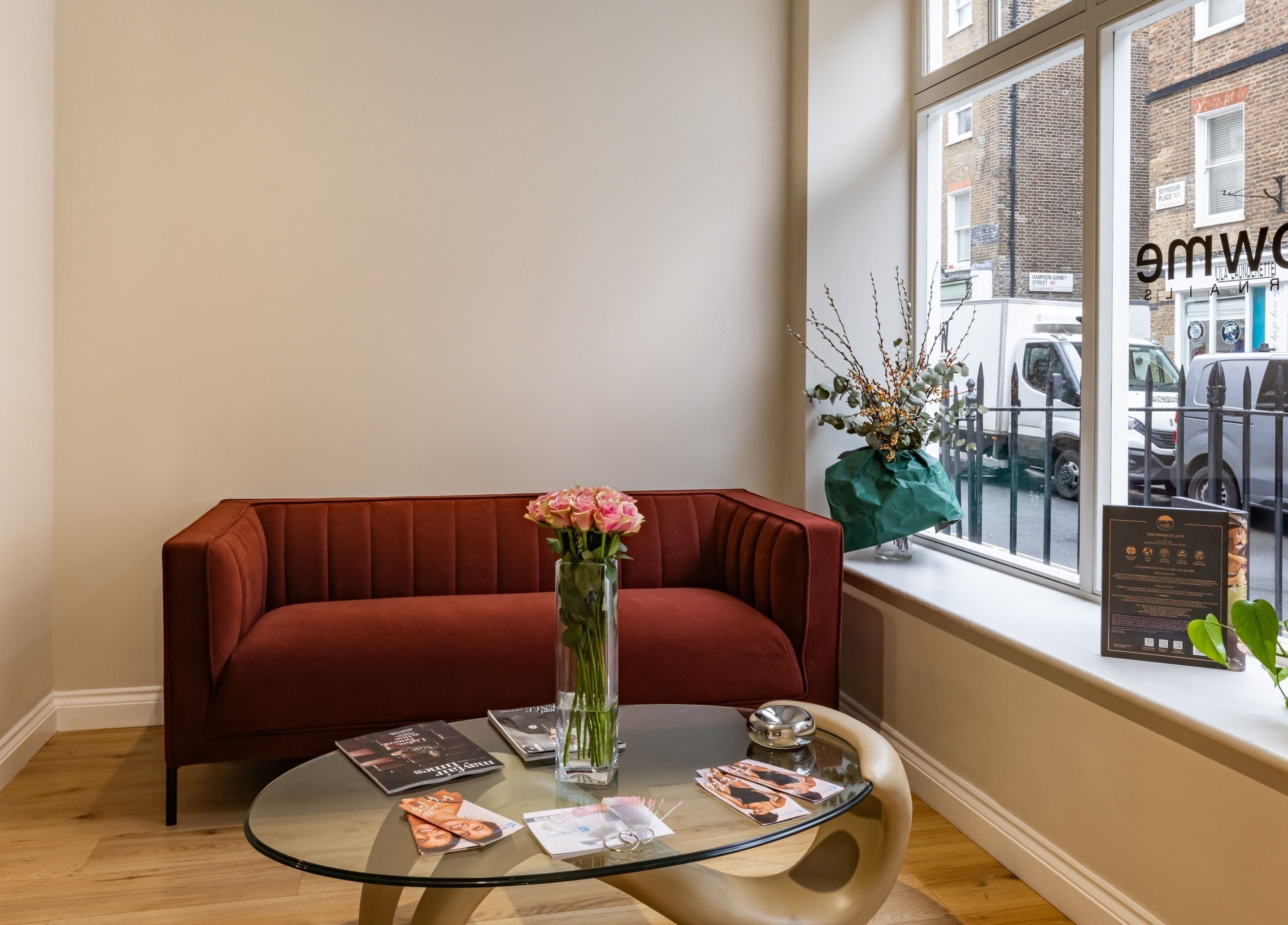 Cozy seating area at Show Me Your Nails, London, England, GB with red sofa and decorative plants.