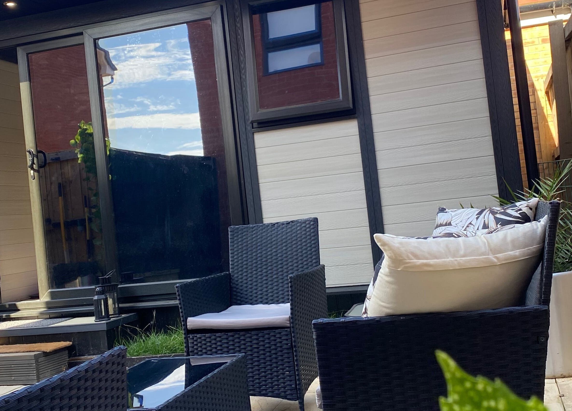 Outdoor seating area at Healing Muscles Northampton, Overstone, England, GB showcasing rattan chairs and a small table.