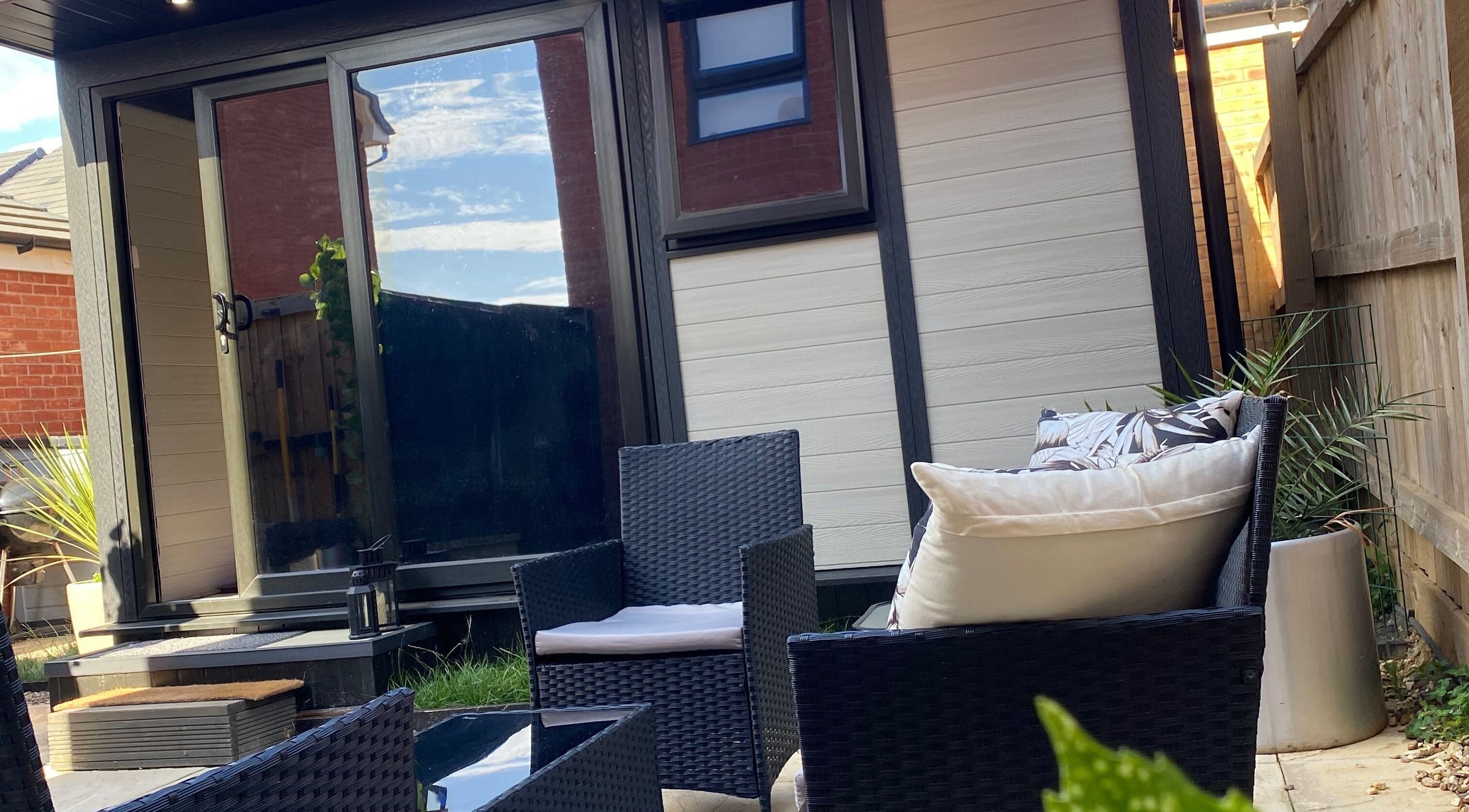 Outdoor seating area at Healing Muscles Northampton, Overstone, England, GB showcasing rattan chairs and a small table.