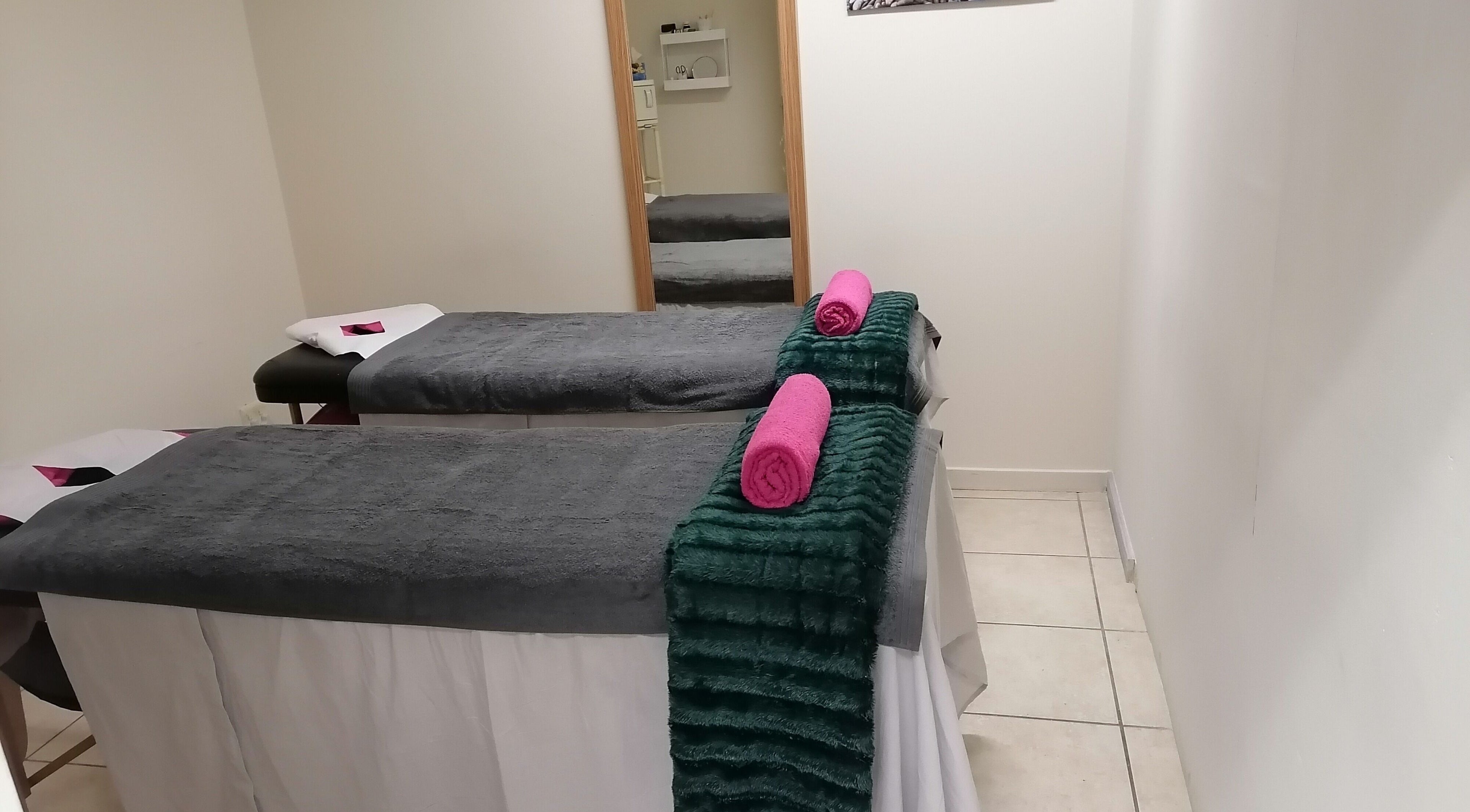 Relaxing massage room at Empire Wellness Spa, Jeffreys Bay, Eastern Cape, ZA with twin beds and fluffy towels.