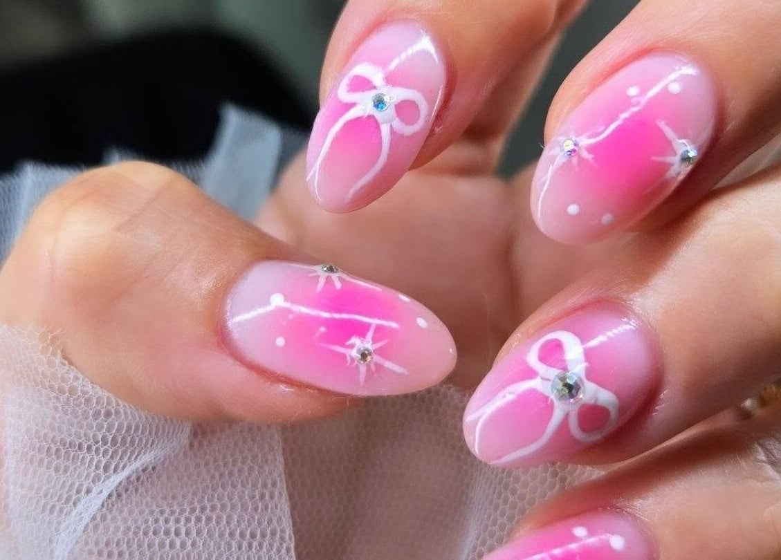 Elegant pink nail art with white bows at Plush Nail Salon Ii, Glenview, Illinois, US.