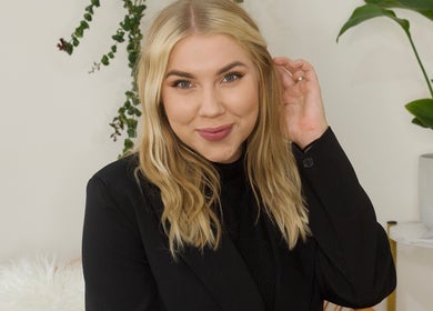 Professional at Alexandra Beauty in Norwich, England, GB, smiling warmly with lush plants as backdrop.