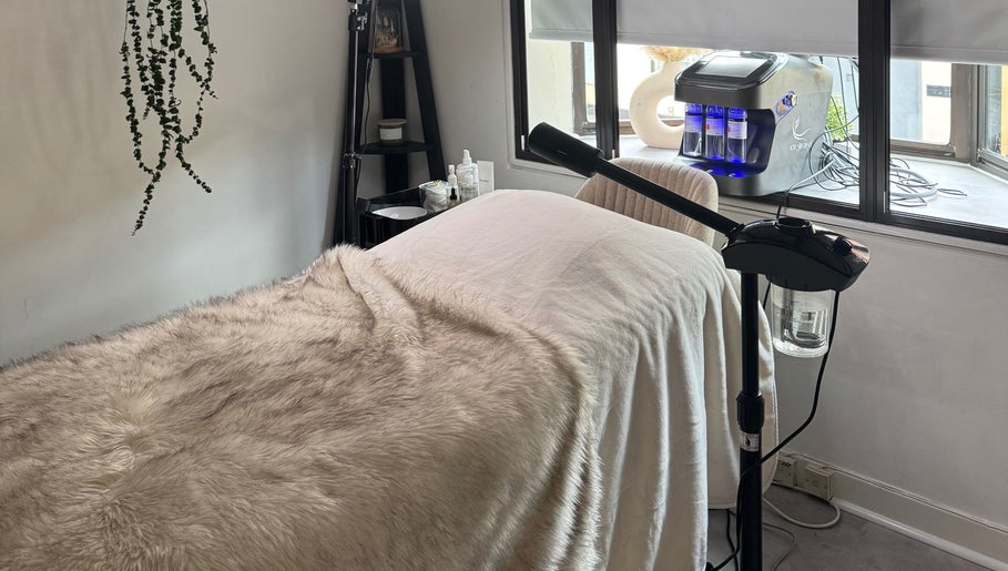 Cozy treatment room at Alexandra Beauty, Norwich, England, GB, featuring soft fur throws and modern equipment.