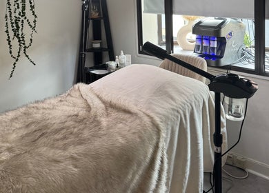 Cozy treatment room at Alexandra Beauty, Norwich, England, GB, featuring soft fur throws and modern equipment.