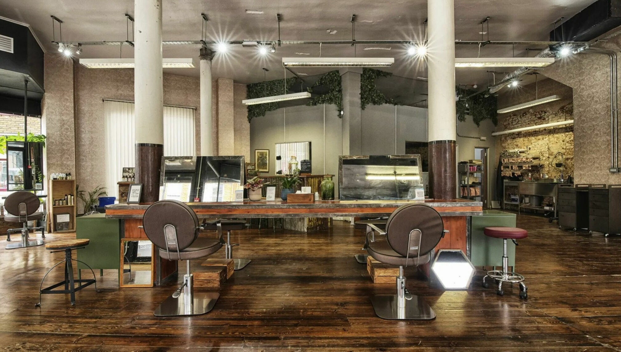 Spacious salon interior at The Bohemians, London, England, GB featuring rustic wooden flooring and stylish chairs.