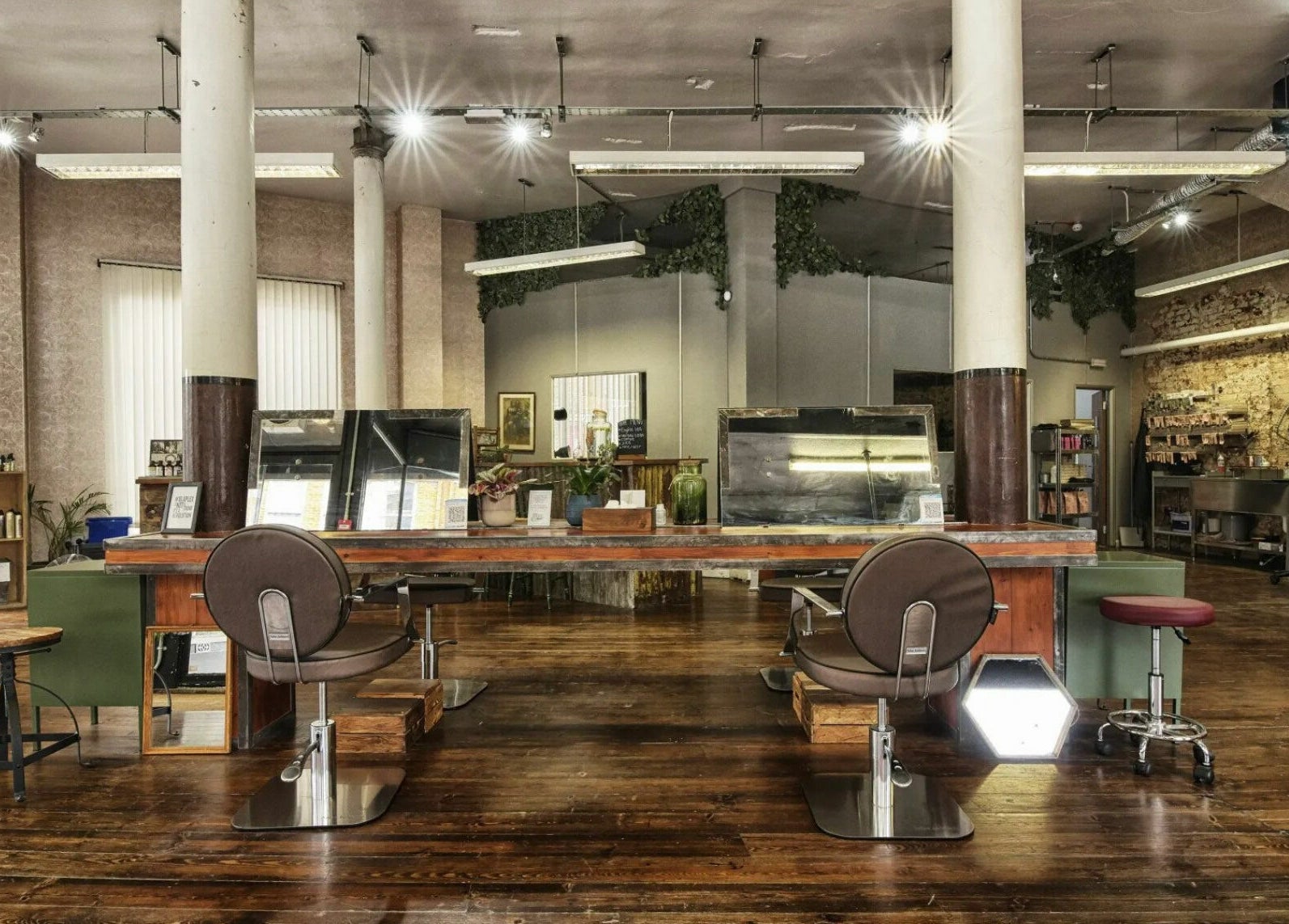 Spacious salon interior at The Bohemians, London, England, GB featuring rustic wooden flooring and stylish chairs.