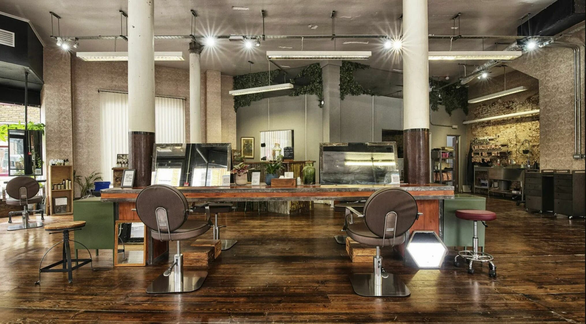 Spacious salon interior at The Bohemians, London, England, GB featuring rustic wooden flooring and stylish chairs.