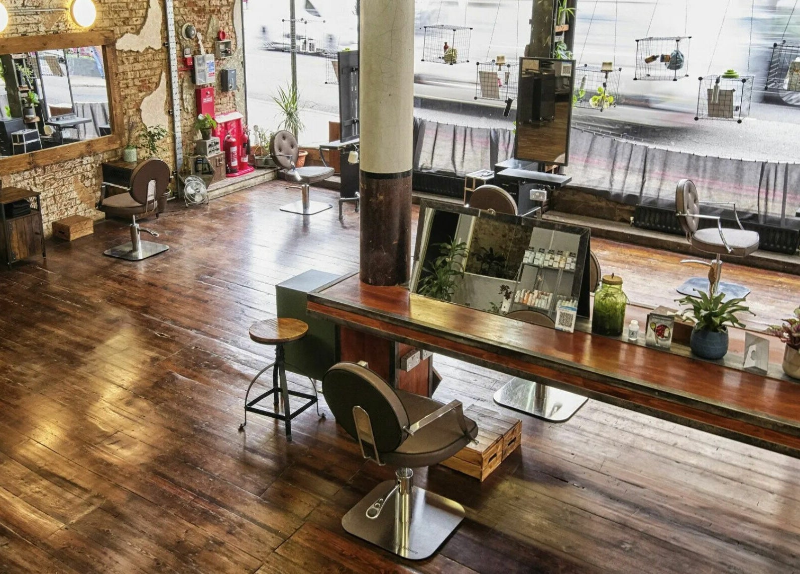 Stylish interior of The Bohemians salon in London, England, GB showcasing rustic wood floors and modern decor.